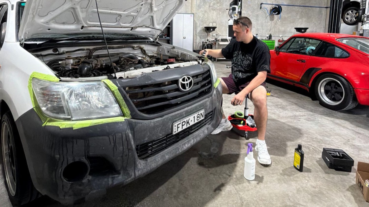 HALO technician masking off and restoring a Toyota Hilux headlight in the workshop